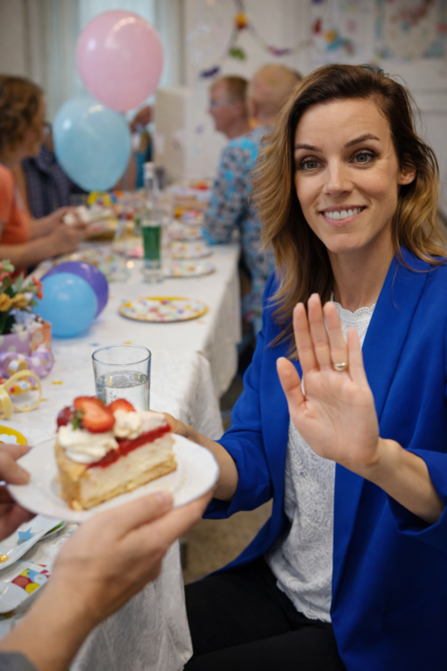 vrouw wijst taartje af op feesttafel